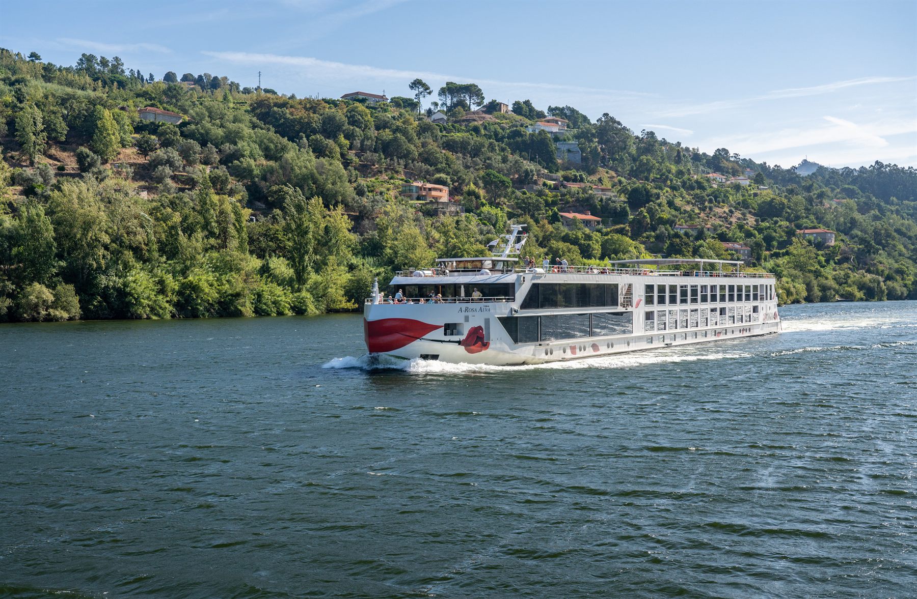 River cruise ship sailing past green wooded hills on the Douro, Portugal